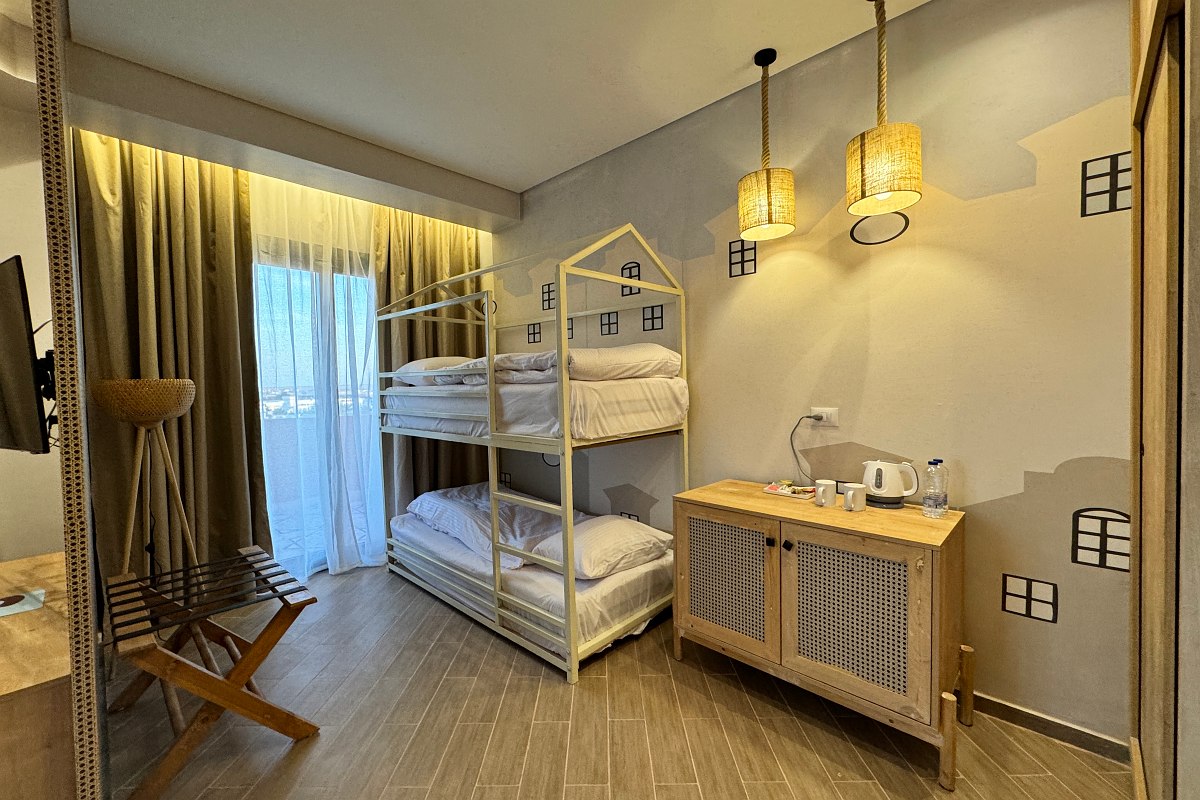 Helles, stilvolles Hotelzimmer mit zwei Einzelbetten, gemütlichem Sitzbereich und modernem Ambiente.