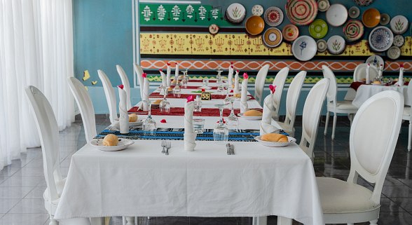 Eleganter Restaurantbereich mit weiß gedeckten Tischen, dekorativen Tellern an der Wand und stilvoller Atmosphäre.