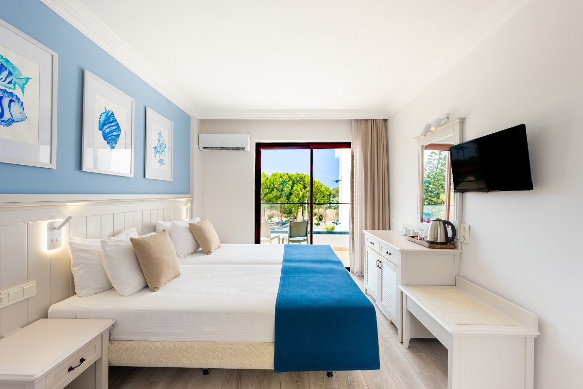 Helles Hotelzimmer mit zwei Einzelbetten, grüner Deko, Balkonzugang und modernem Design.