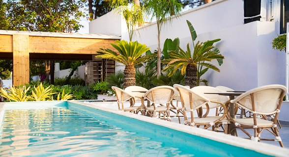 Luftaufnahme eines Resorts mit mehreren Pools, einer Wasserrutsche und einem Basketballfeld. Liegestühle sind rund um die Pools verteilt.