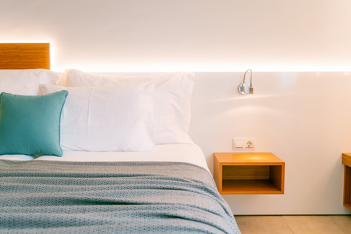 Hell eingerichtetes Zimmer mit zwei Einzelbetten, violettem Sofa, Poolblick, Wohnbereich und Schlafbereich, zwei Klimaanlagen, Nichtraucher Zimmer, Fliesenboden.