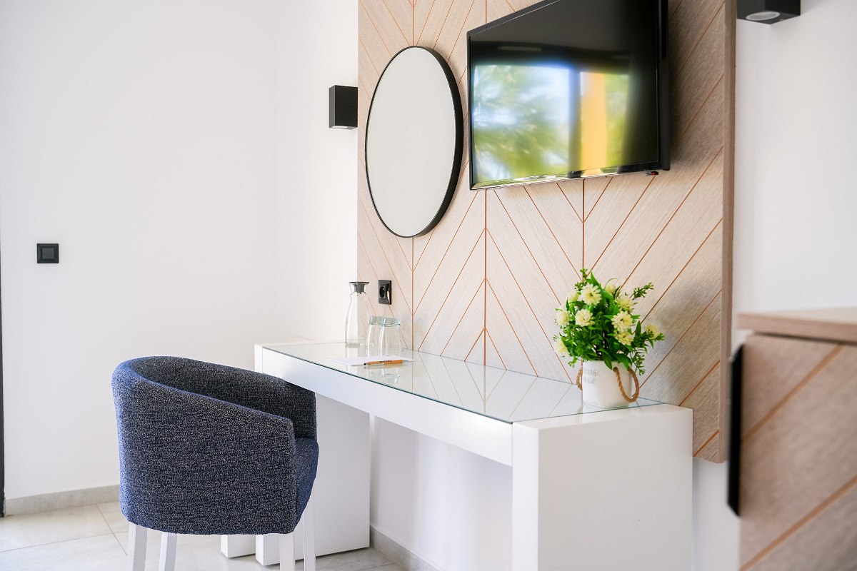 A sleek modern bathroom featuring a black vanity with a white vessel sink, a large rectangular mirror, a walk-in glass shower, and neutral beige tiles.