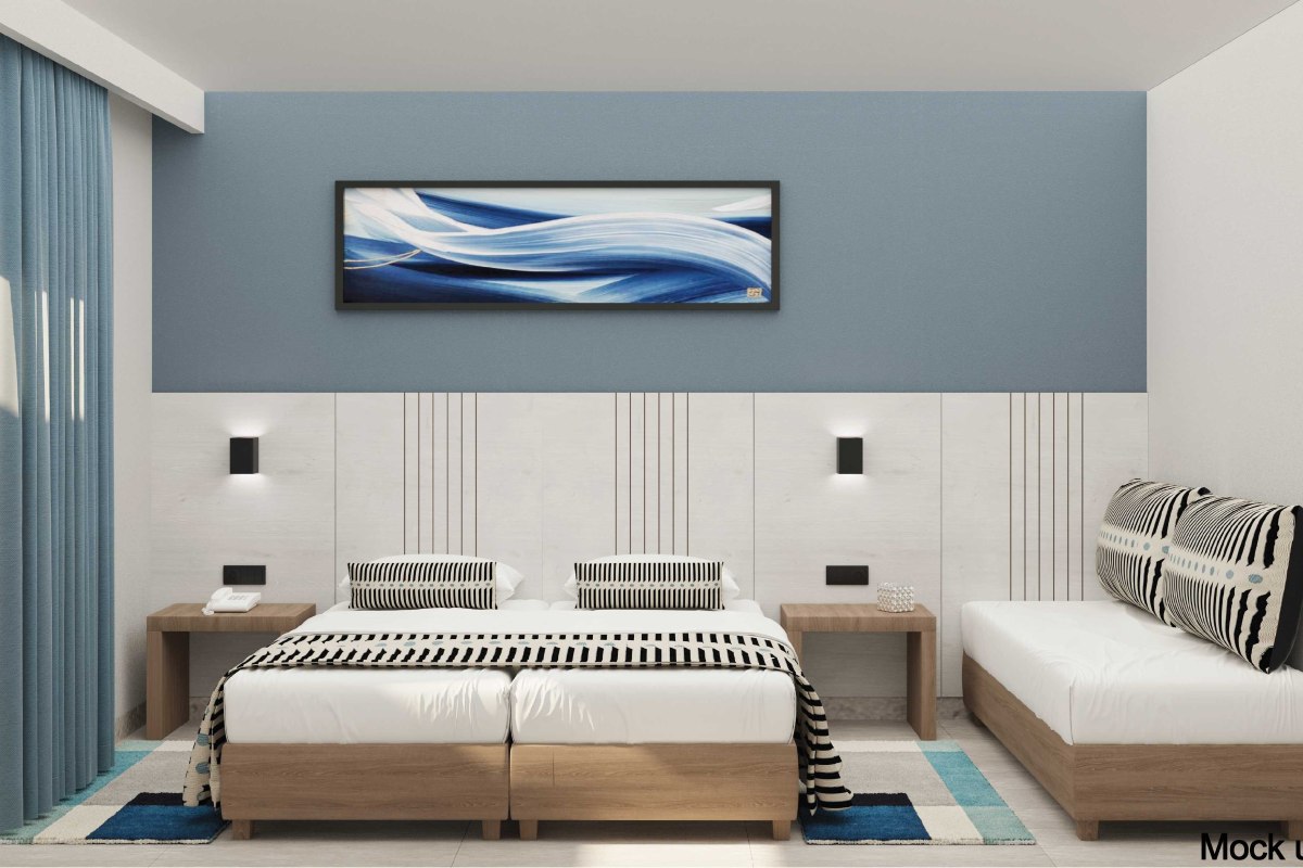 A bright hotel room with three single beds, blue bedding accents, a playful teepee, a patterned blue wall, and a balcony with outdoor seating.