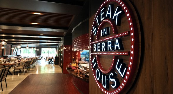 A stylish steakhouse interior with a glowing round sign reading 
